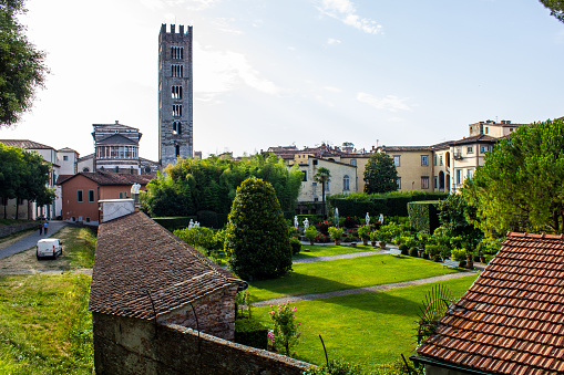Lucca, Italy - July 9, 2017: View of Pfanner Palace and Garden from the City Walls with San Frediano Basilica and Bell Tower in the Background