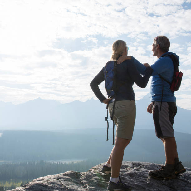 istock Couple stand on rock ledge above a valley and embrace 1282327855