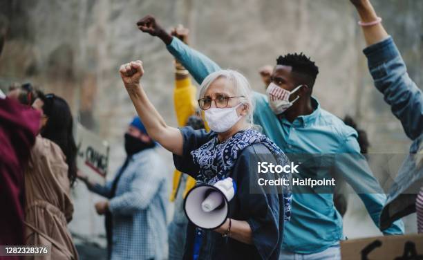 Group Of People Activists With Raised Fists Protesting On Streets Protests Demonstration And Coronavirus Concept Stock Photo - Download Image Now