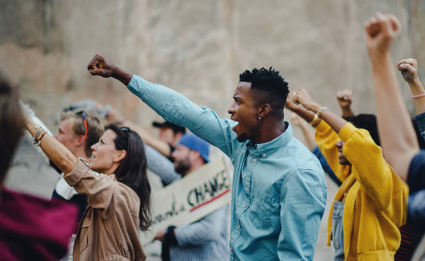 istock Group of people activists with raised fists protesting on streets, protests demonstration concept. 1282328453