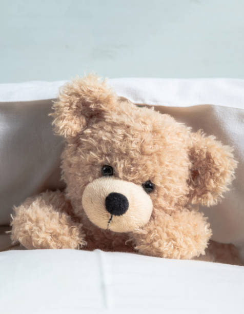 istock Kids bedtime. Cute teddy playing with pillows in bed, 1282328502