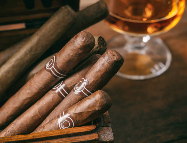 gros plan de cigares cubains sur le bureau en bois, verre flou de brandy - cigar whisky bar cognac photos et images de collection