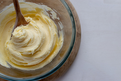 Creamy vanilla buttercream made from icing sugar and butter in a glass bowl - baking background - copy space