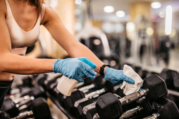 istock Fit woman cleaning dumbbells with disinfectant spray 1282331237