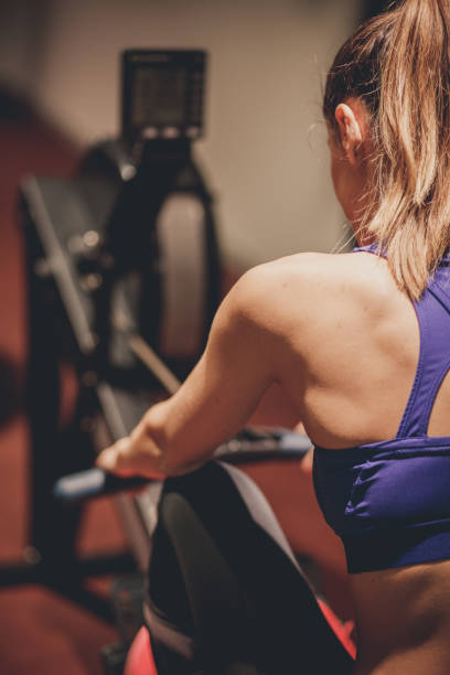 istock Rear view of a female athlete using a rowing machine at the gym 1282331269