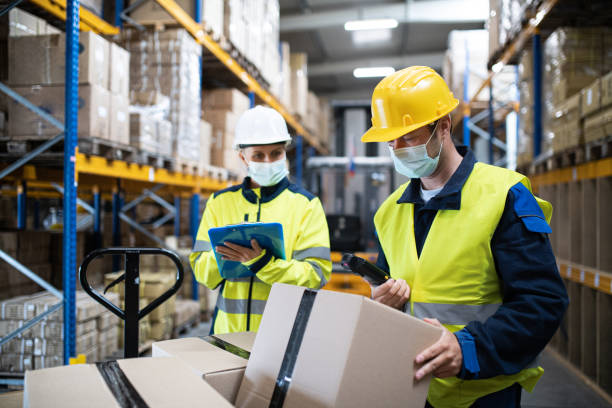 istock Workers with face mask working indoors in warehouse, coronavirus concept. 1282332945