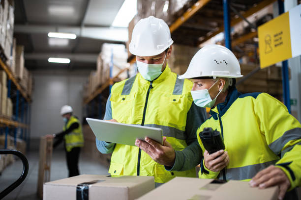 istock Workers with face mask working indoors in warehouse, coronavirus concept. 1282332957
