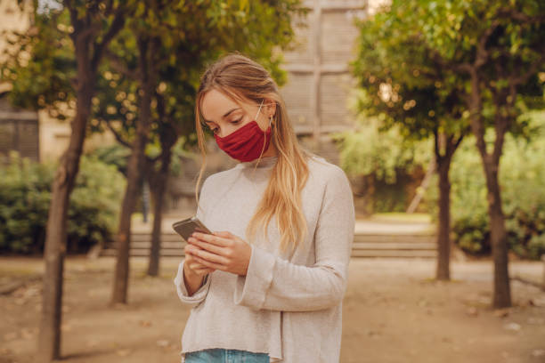 istock Girl wearing mask checking her phone 1282334233