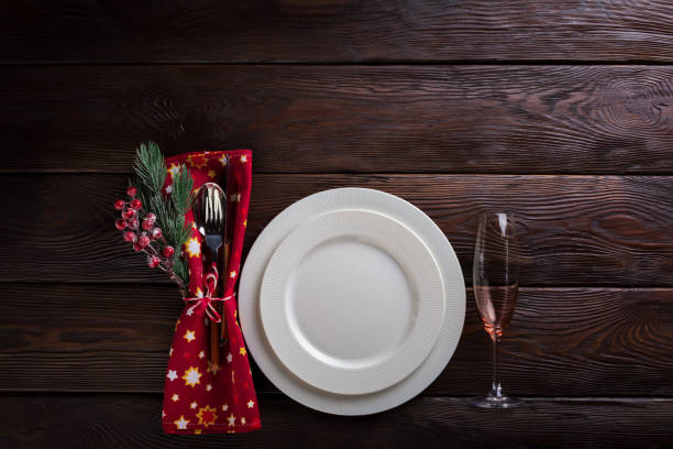 Christmas table setting with empty white plates, wineglass, cutlery and table napkin.