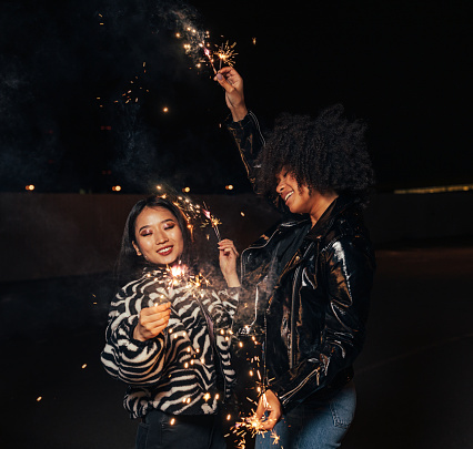 Two happy girls with sparklers enjoying a party at night