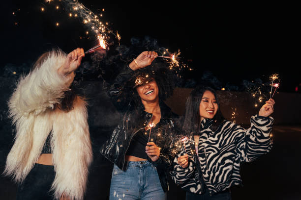 istock Three happy girls waving sparklers while walking together at night 1282339009