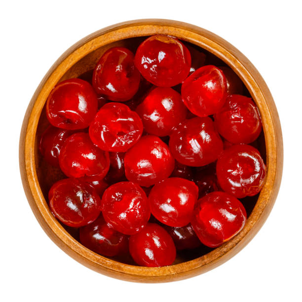 Maraschino cherries, cocktail cherries, in a wooden bowl Maraschino cherries in a wooden bowl. Also cocktail cherries, whole red fruits of Prunus avium, preserved and sweetened in sugar syrup, used as garnish. Close-up from above, isolated macro food photo. maraschino cherry stock pictures, royalty-free photos & images