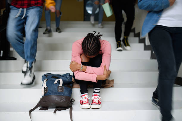 joven estudiante deprimido con máscara facial sentado en el piso de la universidad o la universidad, concepto de coronavirus. - depression fotografías e imágenes de stock