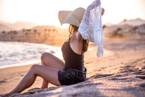 istock Beautiful boho model in a hat poses on the beach in the sun 1282340288