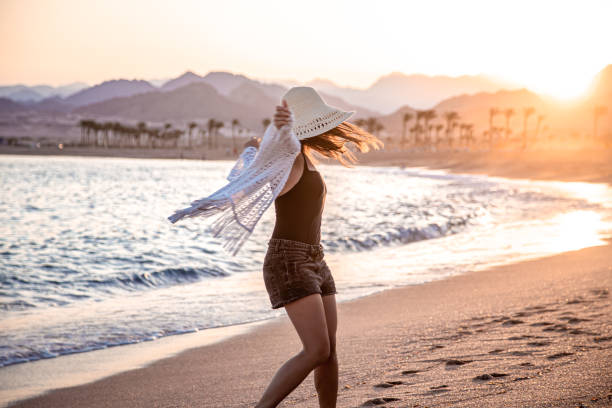 istock Woman at sunset on the beach in a hat. 1282340294