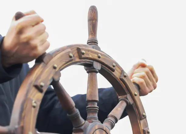 the helm of the ship is in good hands. male hands hold the steering wheel.