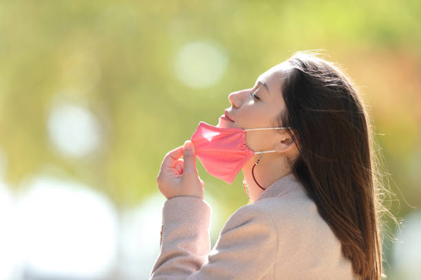 frau zieht maske atmen frische luft in einem park - entrepreneur lifestyles nature environment stock-fotos und bilder