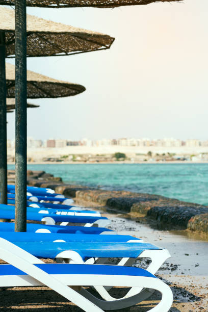 istock Blue plastic sun loungers under umbrellas on the beach. 1282343491