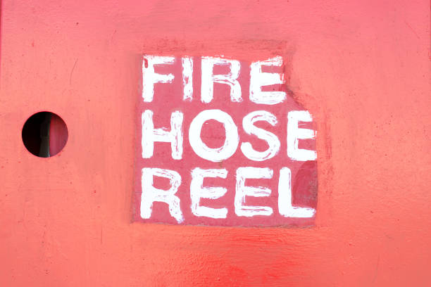 istock Inscription by white paint Fire Hose Reel on a red wall. 1282343648