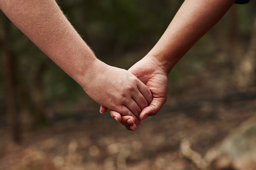 Cropped shot of two women holding hands outdoors