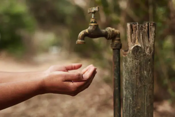 Cropped shot of an unrecognisable woman holding her hands out for water from a tap in nature