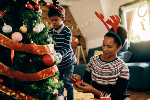 istock Happy black mother and son enjoying while decorating Christmas tree at home. 1282345322