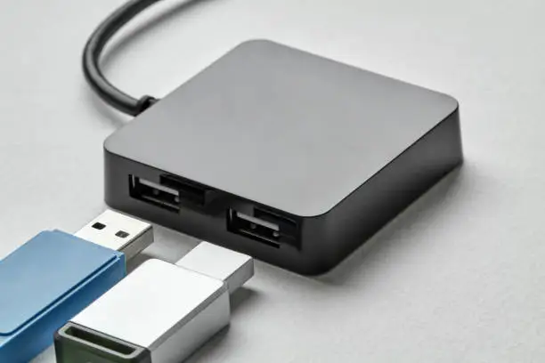 Photo of Black portable USB hub for four connections with usb flash drives on a white background. Bus povered. Closeup, selective focus