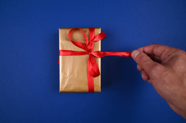 istock Hand untie gift wrapping on blue background 1282345416