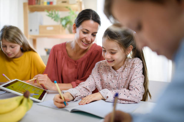 gruppo di bambini di homeschooling con insegnante che studia all'interno, concetto di coronavirus. - child digital tablet mother teaching foto e immagini stock