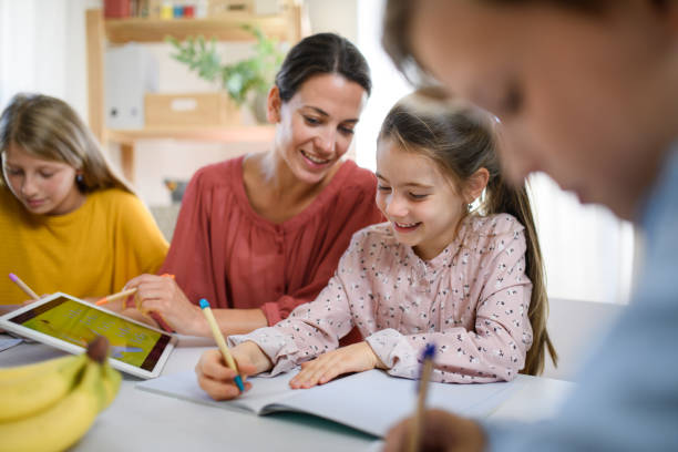Group of homeschooling children with teacher studying indoors, coronavirus concept. Group of homeschooling children with parent teacher studying indoors, coronavirus concept. assistant stock pictures, royalty-free photos & images