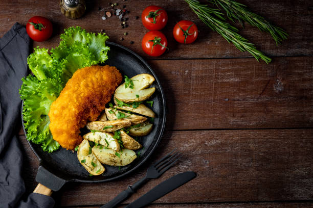 istock Pork schnitzel with baked potatoes in a pan, top view, free space for text 1282346781