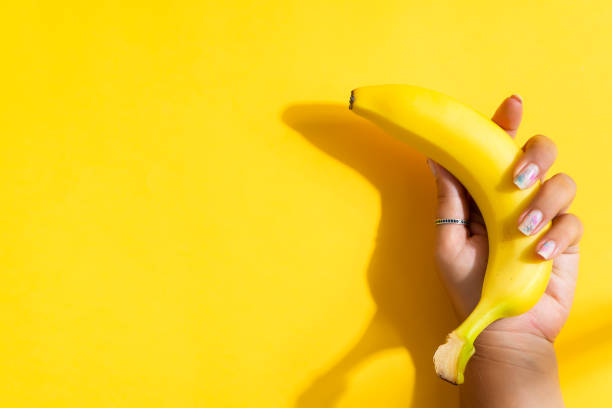 istock Ripe fresh banana fruit in a woman's hand with shadow. 1282346850
