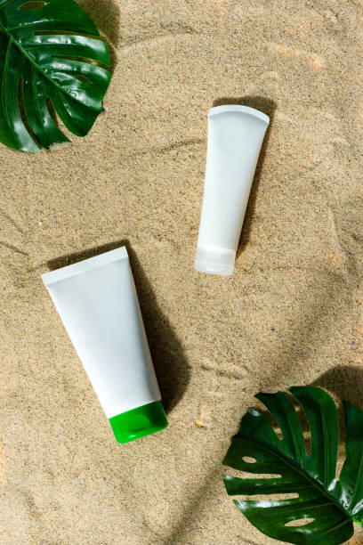istock Mock-up cream plastic tubes on a sand beach background. 1282347969