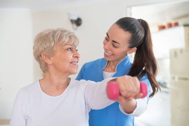 istock Physical therapist helping a senior man at home with her physiotherapy routine using weights 1282348201