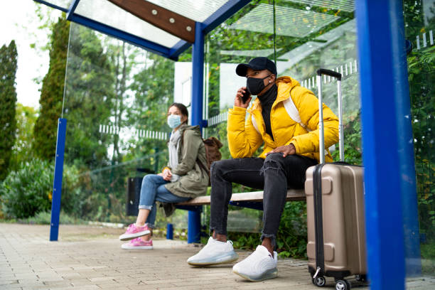 istock Young people with smartphone on bus stop outdoors in town. Coronavirus concept. 1282349679