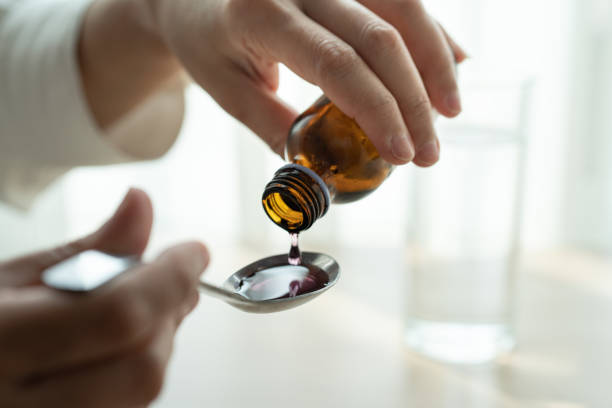 woman hand pouring medication or cough syrup from bottle to spoo - maple imagens e fotografias de stock