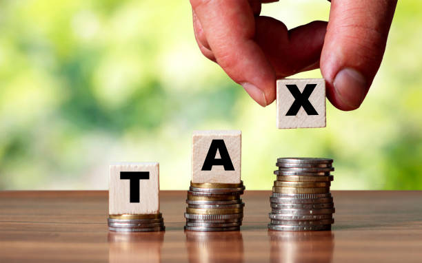 istock Tax word on wooden cube shape stacked on steps with coin 1282350285