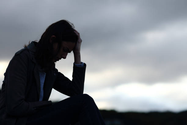 profile of a sad woman silhouette complaining outdoors - guilt imagens e fotografias de stock