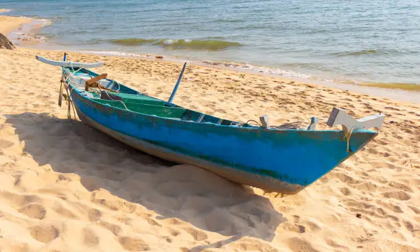 Photo of Abandoned fishing boat on the sandy seashore. Old wooden boat on tropical beach.