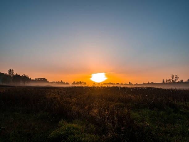 istock Orange sunrise over a meadow in fog. 1282354493