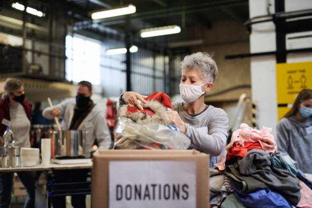 volontari che lavorano con cibo e vestiti nel centro di donazioni di beneficenza della comunità, concetto di coronavirus. - charity and relief work foto e immagini stock