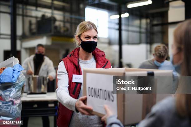 Volunteers Working With Food And Clothes In Community Charity Donations Center Coronavirus Concept Stock Photo - Download Image Now