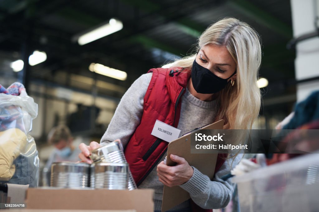 Woman volunteer in community charity donation center, food bank and coronavirus concept. Young woman volunteer in community charity donation center, food bank and coronavirus concept. Volunteer Stock Photo