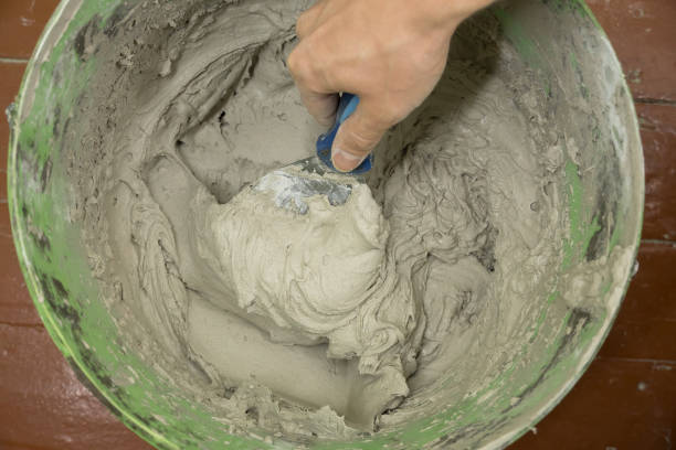 istock A worker uses a spatula to get a solution of the cement mixture.The master puts the plaster.Handyman repairs the house. A laborer restores a home.Handyman home repair at work 1282354784
