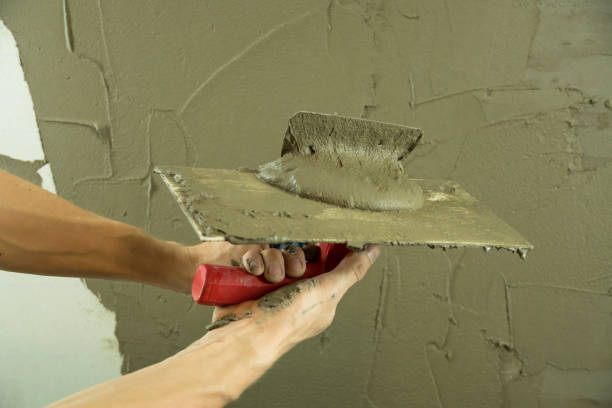 istock A worker plasters the wall with a spatula and applies a cement mix solution. The repairman lays the plaster on the drywall. Handyman repairs home. Laborer restore dwelling. Specialist covers up cracks 1282354794