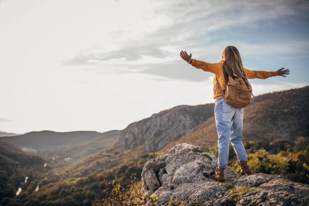 istock Woman standing on mountain peak with arms streched 1282355564