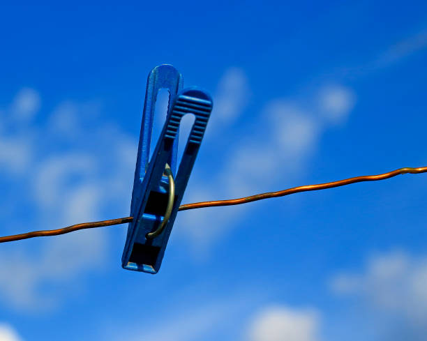 istock One plastic blue clothespin on a copper wire against a soft blue sky 1282356991