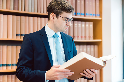 Lawyer in his office reading precedents in thick books thinking about a case