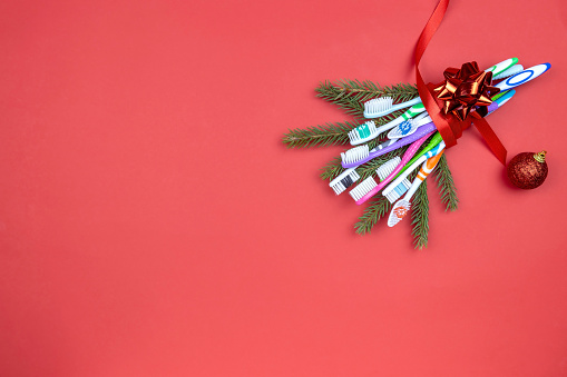 a bouquet of Christmas tree branches and toothbrushes tied with a ribbon on a red background