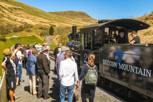 Group of people looking at a vintage narrow gauge steam engine Merthyr Tydfil, Wales - April 2018: Passengers looking at the steam engine which has pulled their train to the terminus station on the Brecon Mountain Railway merthyr tydfil stock pictures, royalty-free photos & images